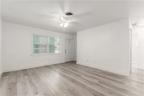 a view of an empty room with a window and a ceiling fan