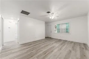 an empty room with wooden floor chandelier fan and windows