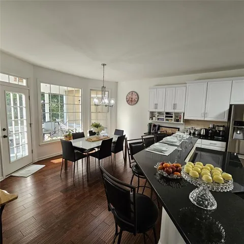 a kitchen with granite countertop stainless steel appliances a sink a stove a refrigerator cabinets and a window