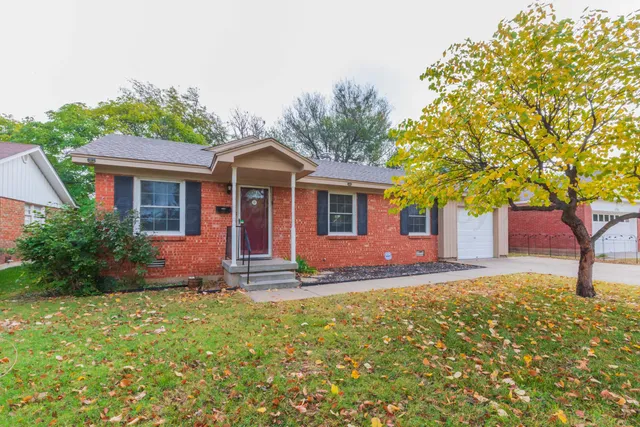 a front view of a house with a garden and trees