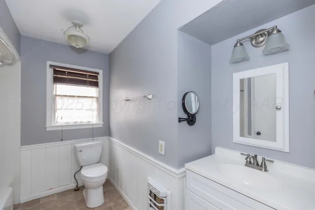 a bathroom with a toilet sink a mirror and window