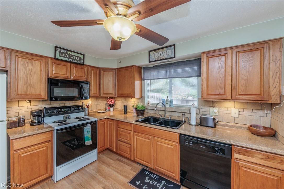 6476 State Road, Unit H8 Cleveland, OH 44134 - Photo 8 of 35 Kitchen featuring black appliances, brown cabinets, light countertops, light hardwood flooring, backsplash, and ceiling fan