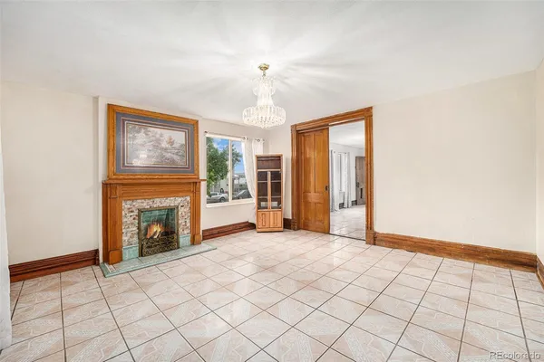 a view of an empty room with window and chandelier fan