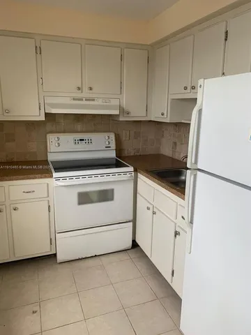 a kitchen with white cabinets and white appliances
