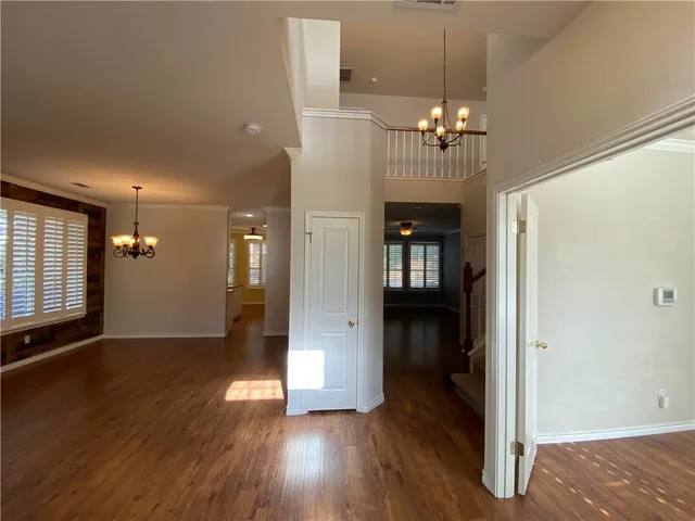 an empty room with wooden floor and a ceiling fan