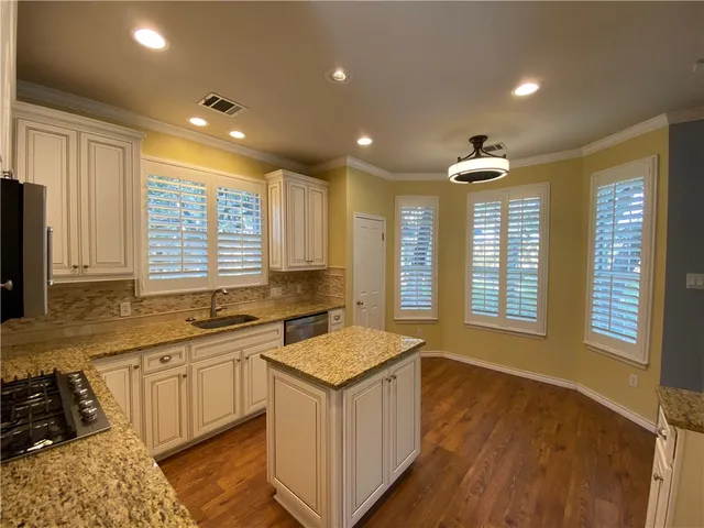 a kitchen with granite countertop kitchen island a sink stainless steel appliances and a counter top space