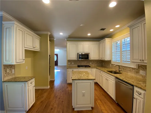 a kitchen with a sink a counter top space stainless steel appliances and cabinets
