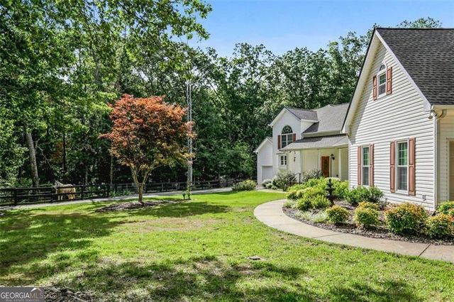 an aerial view of residential house with outdoor space and trees all around