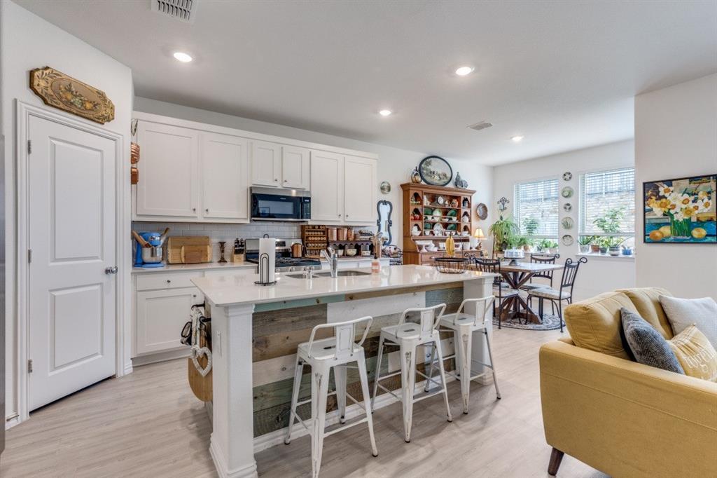 1213 Dragon Street Azle, TX 76020 - Photo 19 of 27 a kitchen with stainless steel appliances granite countertop a stove a sink a dining table and chairs