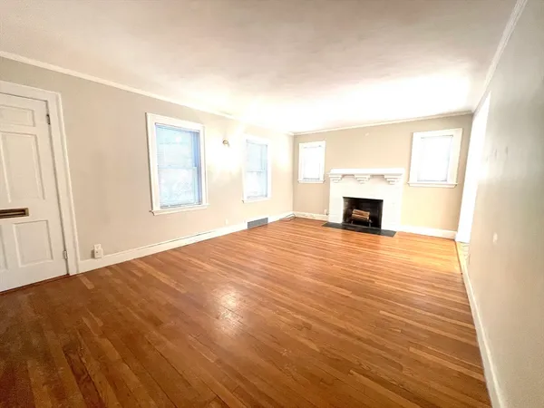 a view of empty room with wooden floor and fireplace
