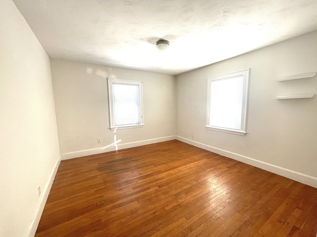 76 Cloverdale Road, Unit 76 Newton, MA 02461 - Photo 7 of 10 an empty room with wooden floor and windows