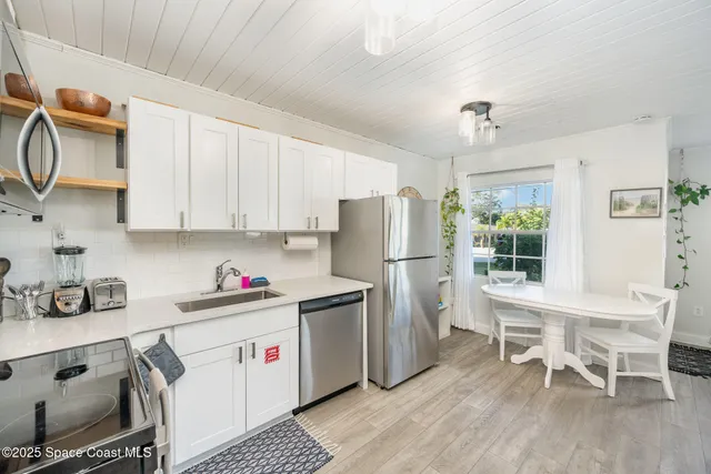 a kitchen with stainless steel appliances a stove a sink dishwasher a refrigerator and cabinets with wooden floor