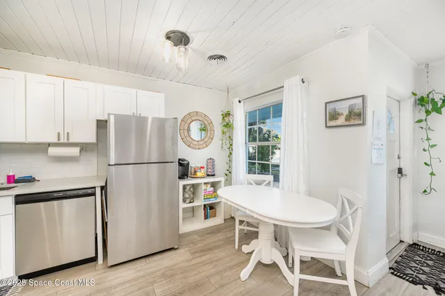 a kitchen with stainless steel appliances a refrigerator a stove a dining table and chairs with wooden floor