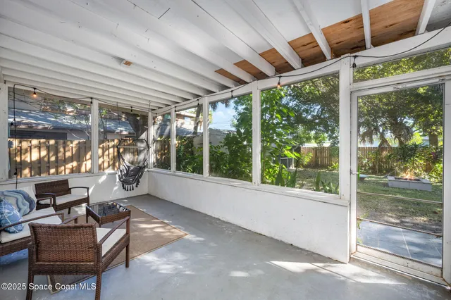 a living room with patio furniture and a floor to ceiling window