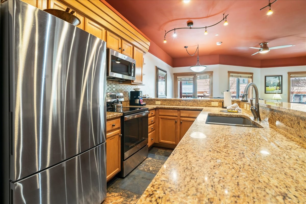 91 River Run Road, Unit 8111 Keystone, CO 80435 - Photo 4 of 43 a kitchen with stainless steel appliances granite countertop a refrigerator a sink dishwasher a stove and a dining table with wooden floor