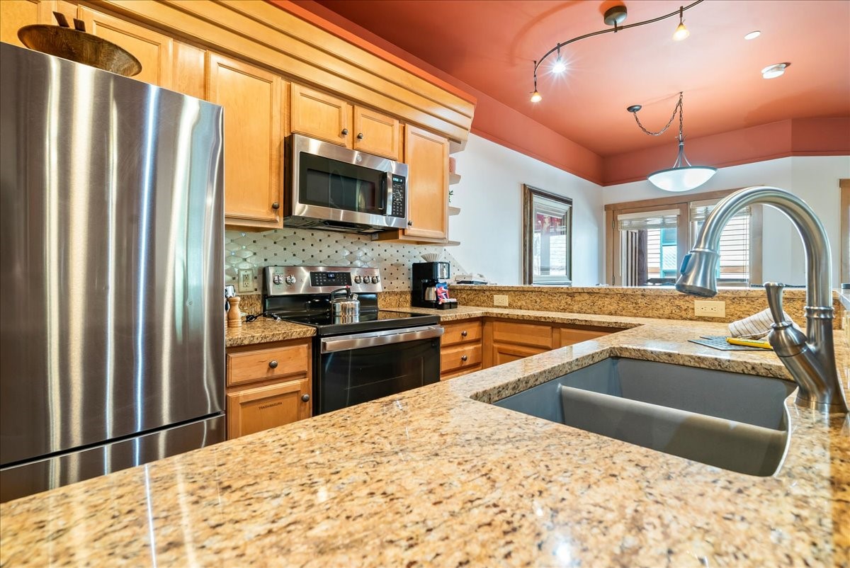 91 River Run Road, Unit 8111 Keystone, CO 80435 - Photo 5 of 43 a kitchen with stainless steel appliances granite countertop a refrigerator a stove and a sink with wooden floor