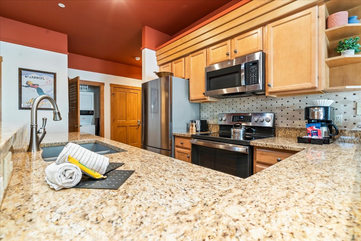 91 River Run Road, Unit 8111 Keystone, CO 80435 - Photo 6 of 43 a kitchen with stainless steel appliances granite countertop a stove top oven a sink a dining table and chairs with wooden floor