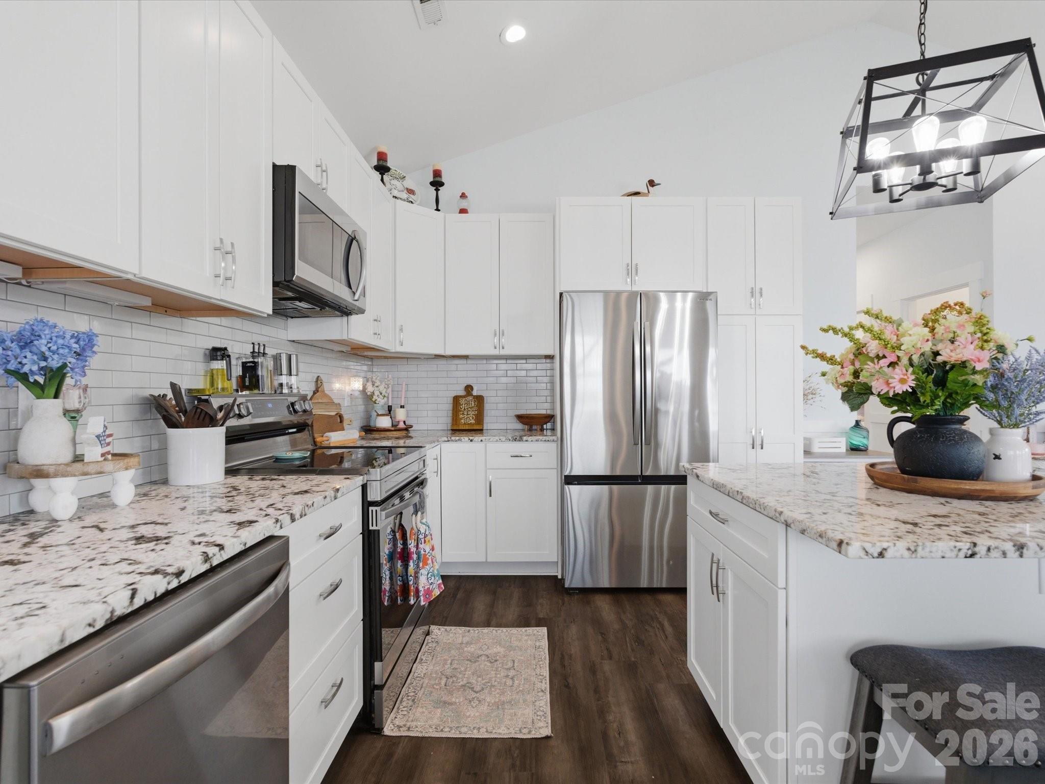 562 Lake Head Road Norwood, NC 28128 - Photo 22 of 43 a kitchen with stainless steel appliances granite countertop a refrigerator a stove a sink dishwasher and white cabinets with wooden floor