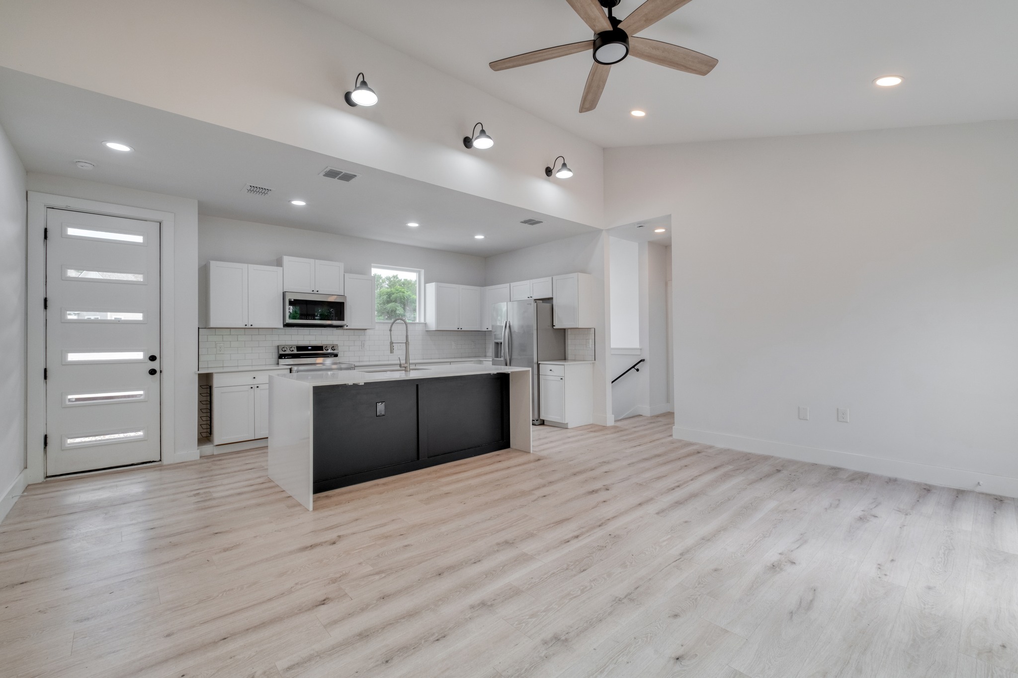5211 Rob-Scott Street Austin, TX 78721 - Photo 3 of 24 A contemporary open-concept space features light wood-look flooring and a functional kitchen with a contrasting island.