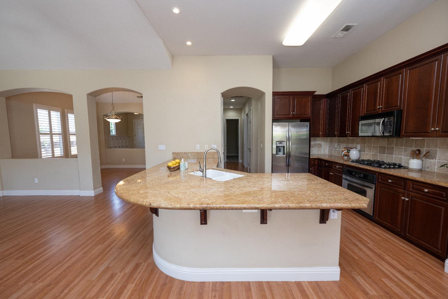1778 Osmun Avenue Clovis, CA 93619 - Photo 13 of 35 a kitchen with stainless steel appliances granite countertop a stove a sink dishwasher and a refrigerator with wooden floor