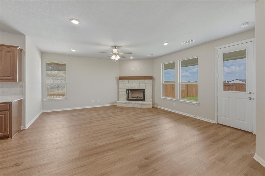 1209 Colca Drive Springtown, TX 76082 - Photo 6 of 24 Spacious living area featuring wood-finish flooring, a corner stone fireplace with a wood mantle, recessed lighting, and a ceiling fan
