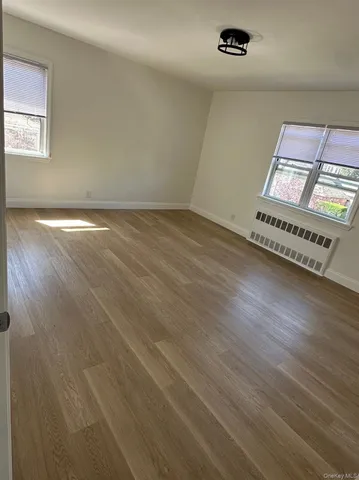 an empty room with wooden floor cabinet and windows