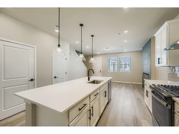 a kitchen with a stove a sink a window and wooden floor