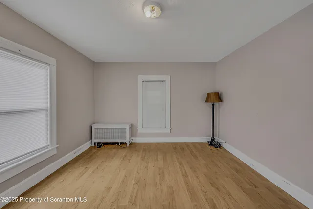 a view of an empty room and room with wooden floor
