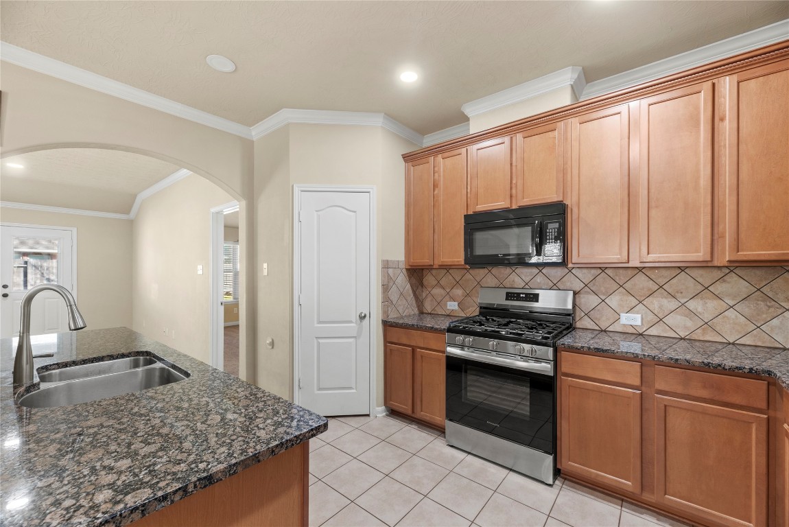 3311 Sabine Spring Lane Katy, TX 77449 - Photo 4 of 16 A spacious, open-concept kitchen at 3311 Sabine Spring Lane featuring granite countertops, rich wood cabinetry, stainless steel appliances, and a seamless flow into the living area—perfect for everyday living and entertaining in Waterstone.