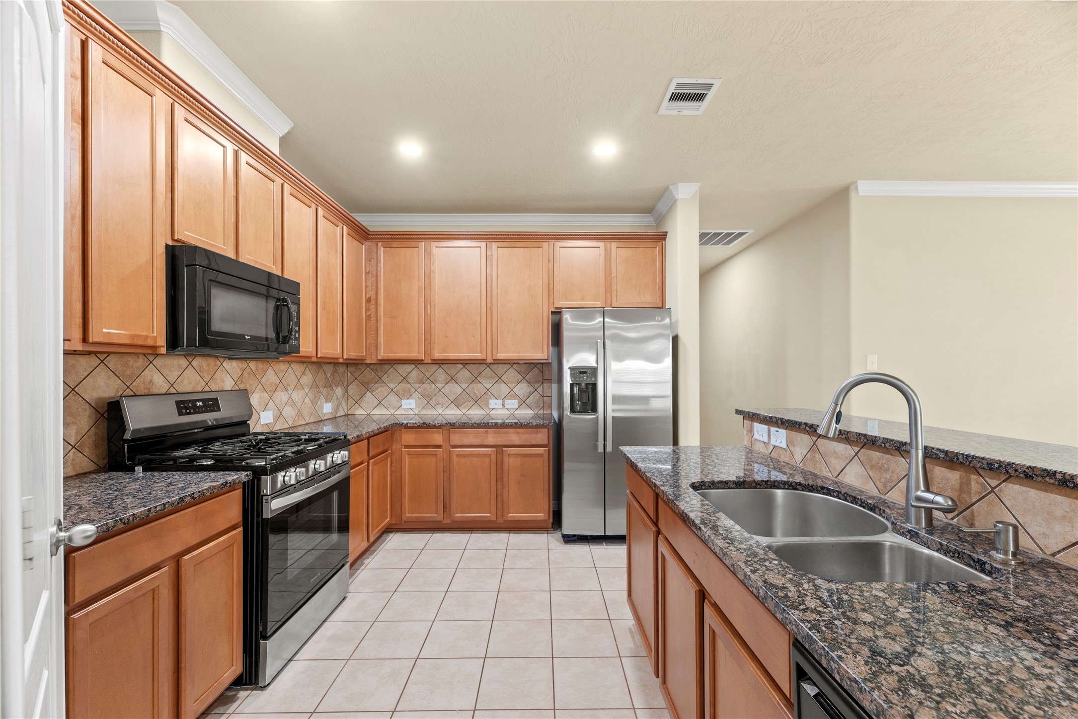 3311 Sabine Spring Lane Katy, TX 77449 - Photo 5 of 16 Enjoy cooking with ample prep space, a gas range, built-in microwave, and expansive granite counter surfaces, all complemented by abundant cabinetry and a functional layout designed for busy households in the heart of Waterstone.