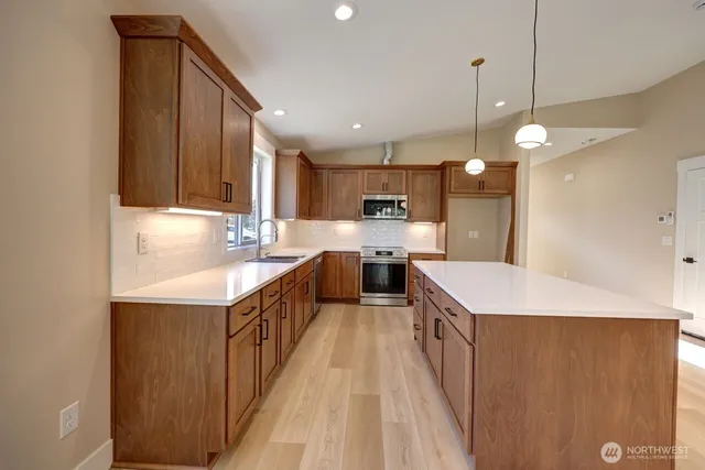 a kitchen with kitchen island granite countertop a sink a counter top space stainless steel appliances and cabinets