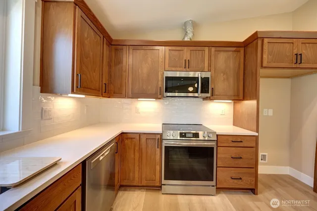 a kitchen with stainless steel appliances a stove a microwave and wooden cabinets