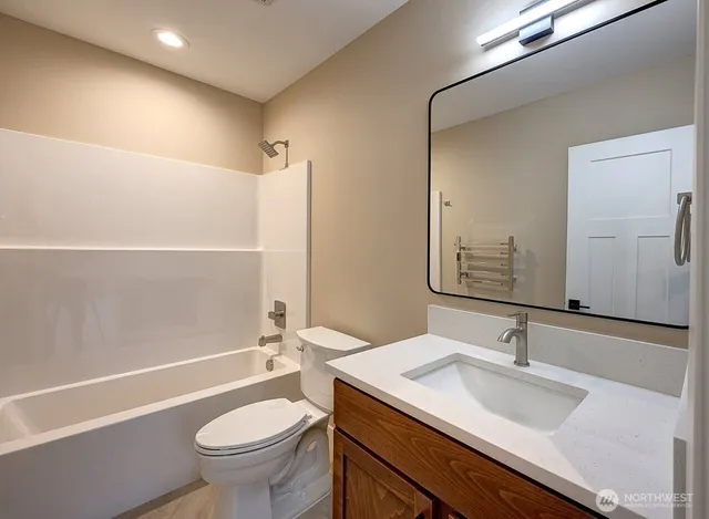 a bathroom with a granite countertop sink a toilet a mirror and bathtub