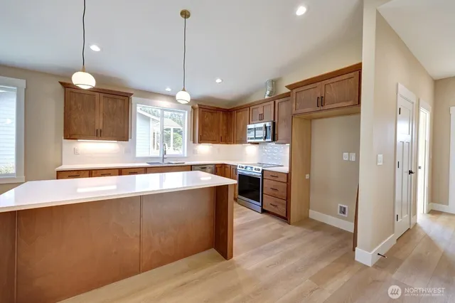 a large kitchen with stainless steel appliances a large counter top a sink a refrigerator and a window