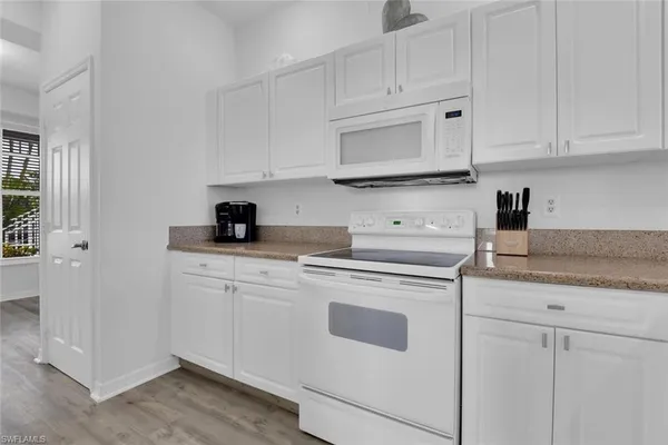 a kitchen with white cabinets and white appliances