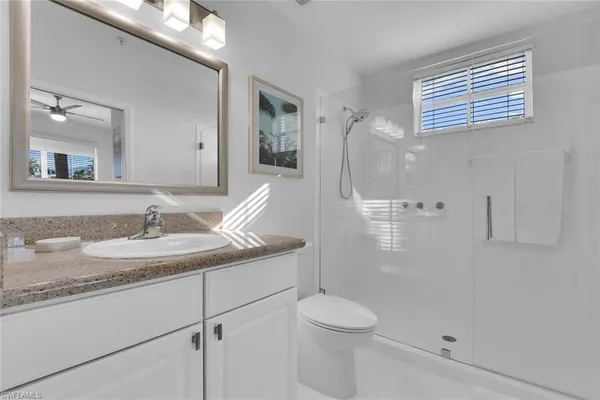 a bathroom with a granite countertop sink toilet and shower