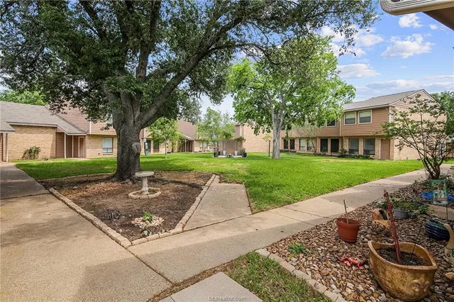 a view of a street with a house and a large tree