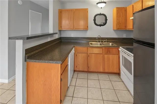 a kitchen with granite countertop a sink a stove a microwave and cabinets