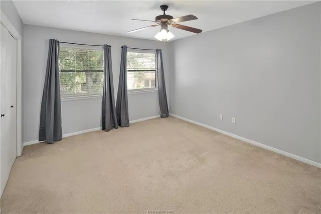 an empty room with windows and fan