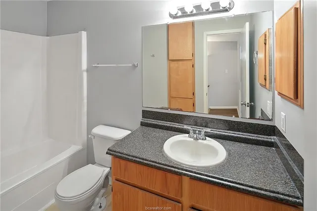 a bathroom with a granite countertop sink toilet and shower