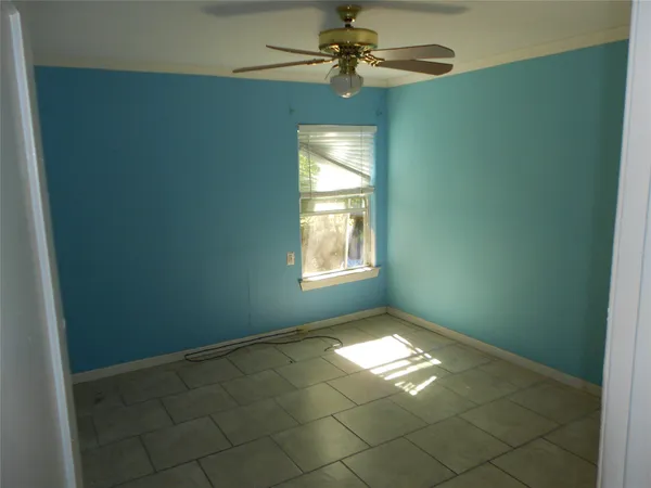an empty room with windows and fan