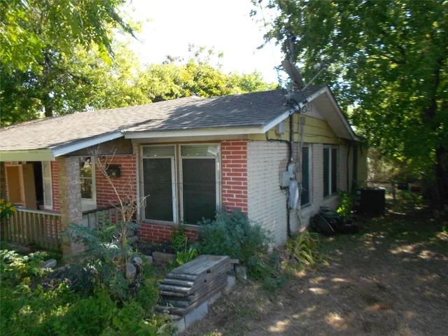 a view of a brick house with a large windows plants and large trees