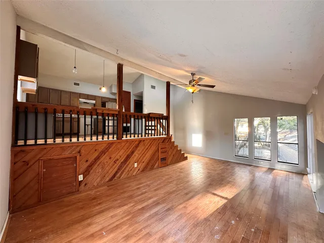 a view of empty room with wooden floor and fan