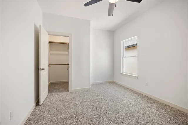 an empty room with chandelier fan and windows