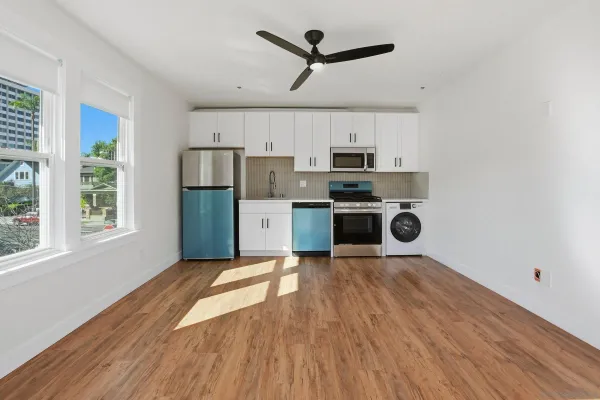 a kitchen with stainless steel appliances a stove a refrigerator and white cabinets with wooden floors