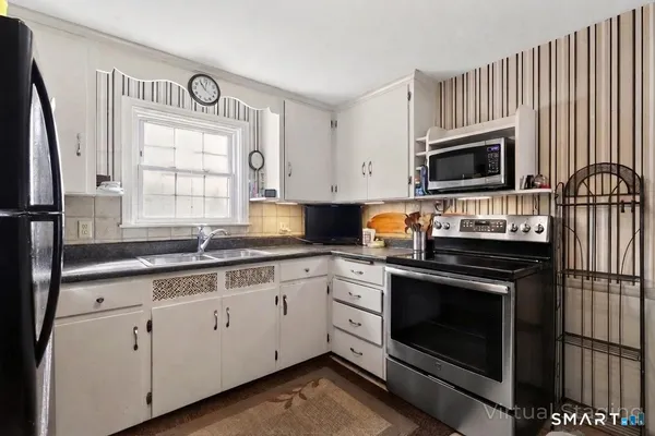 a kitchen with cabinets stainless steel appliances a sink and a window