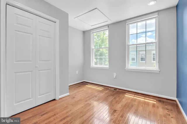 an empty room with wooden floor and windows