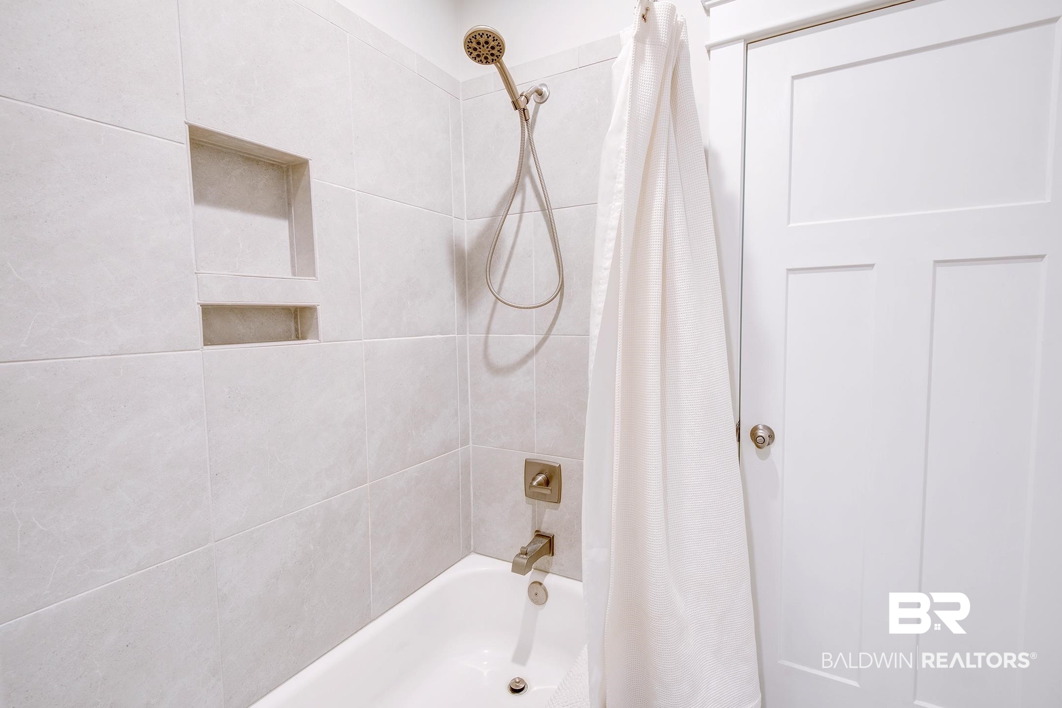 18754 Treasure Oaks Road Gulf Shores, AL 36542 - Photo 37 of 53 Bathtub with light-toned tiled surround, featuring a built-in niche and brushed nickel fixtures