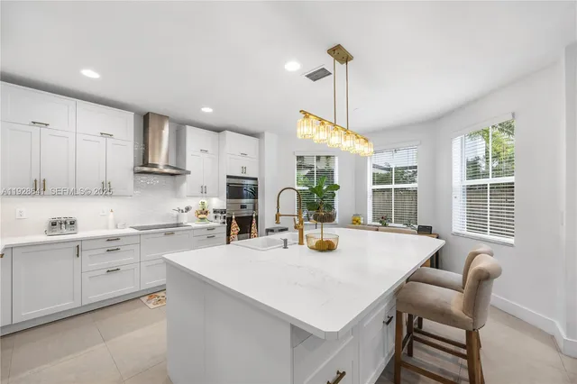 a kitchen with stainless steel appliances kitchen island granite countertop a sink a stove and a refrigerator