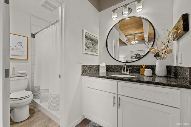 a bathroom with a granite countertop toilet sink and mirror